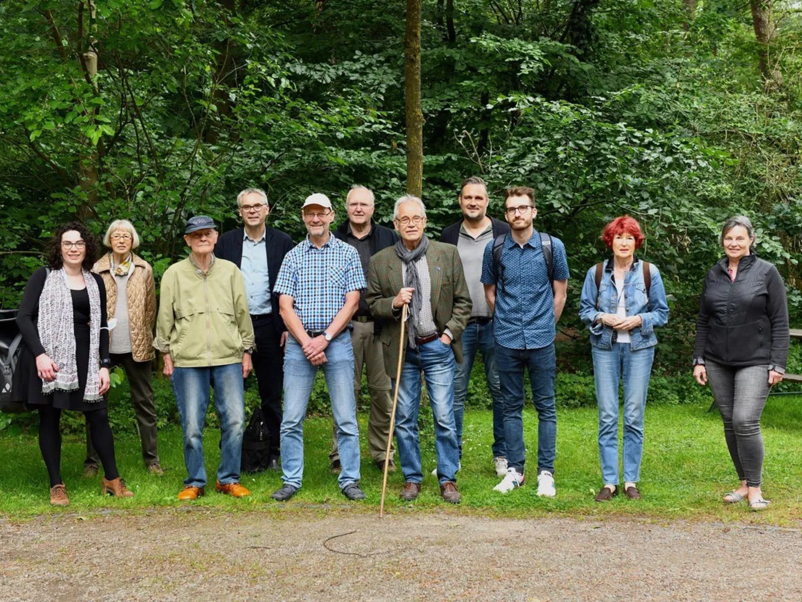 Mehrere Personen auf einer Grünfläche im Wald.